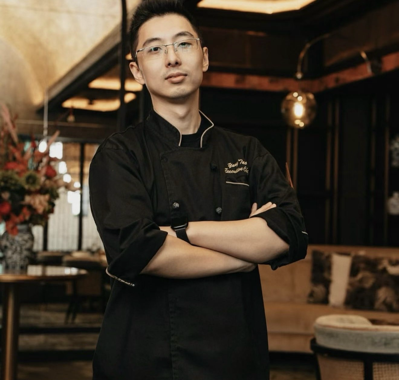 Frankie Yang Tao wearing a black chef jacket in a warmly lit restaurant
